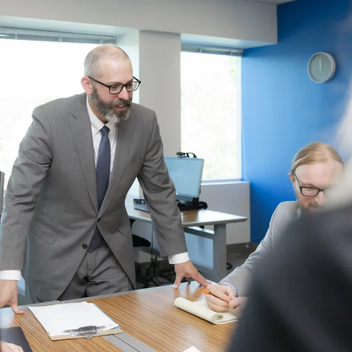 ICE Employees in a meeting with man standing to present