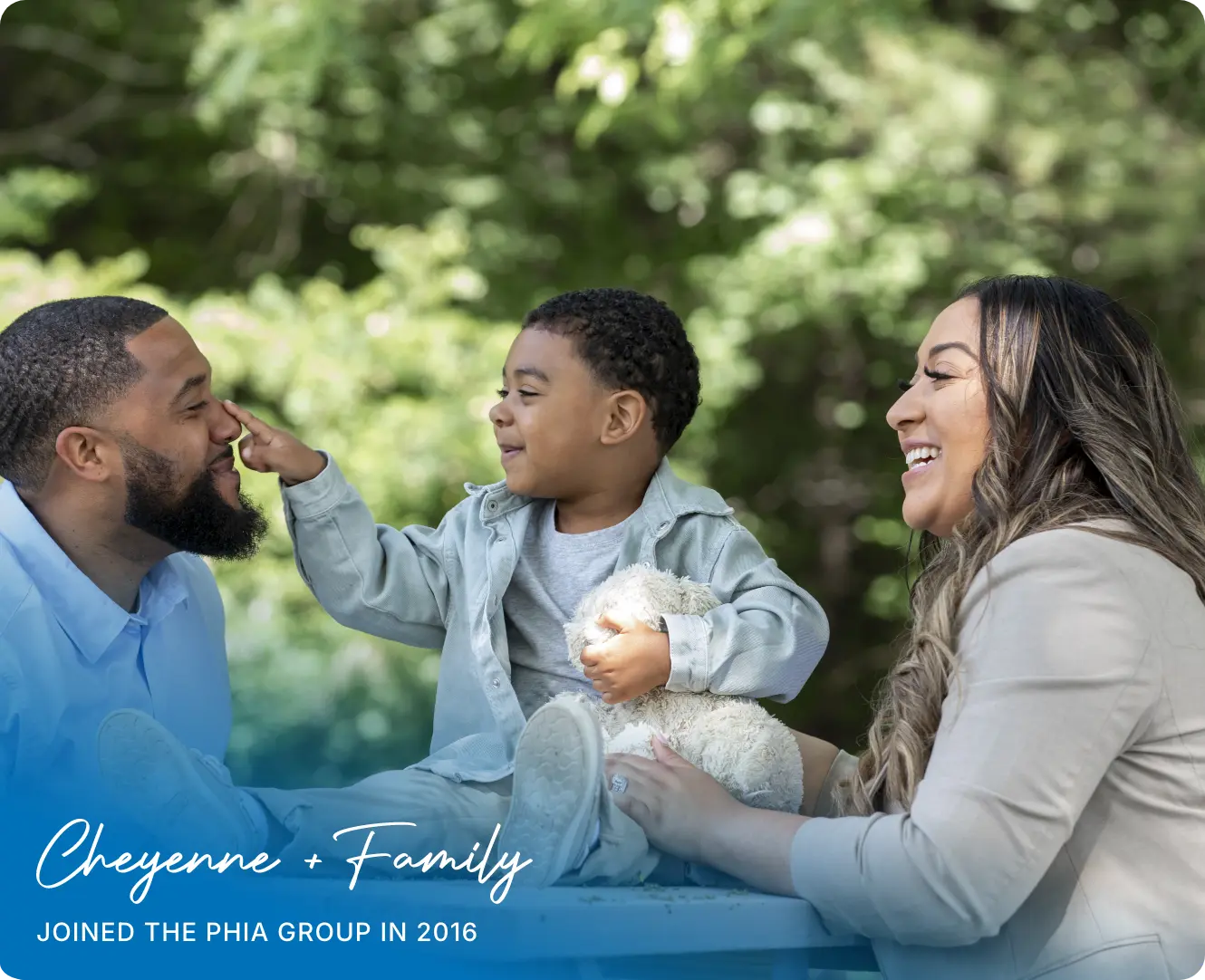 Cheyenne + Family Joined the phia group in 2016 / pictured is her and her husband on a park bench with her kid atop bopping his nose and holding a stuffed animal.